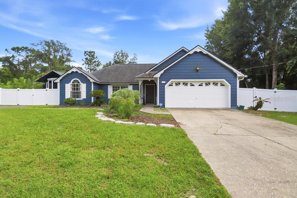 A blue single-story house with a two-car garage and a white vinyl fence — 1714 20TH STREET, ORANGE CITY, FL