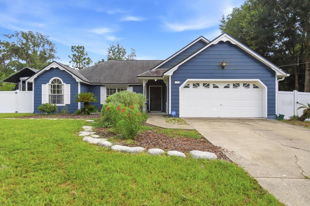 A blue, single-story house with a white garage door, arched window, and a concrete driveway — 1714 20TH STREET, ORANGE CITY, FL
