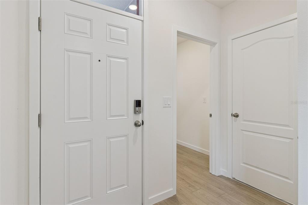 An entryway features a white front door, a closed interior door, and light wood flooring — 1912 HOWARD MESA DRIVE, KISSIMMEE, FL