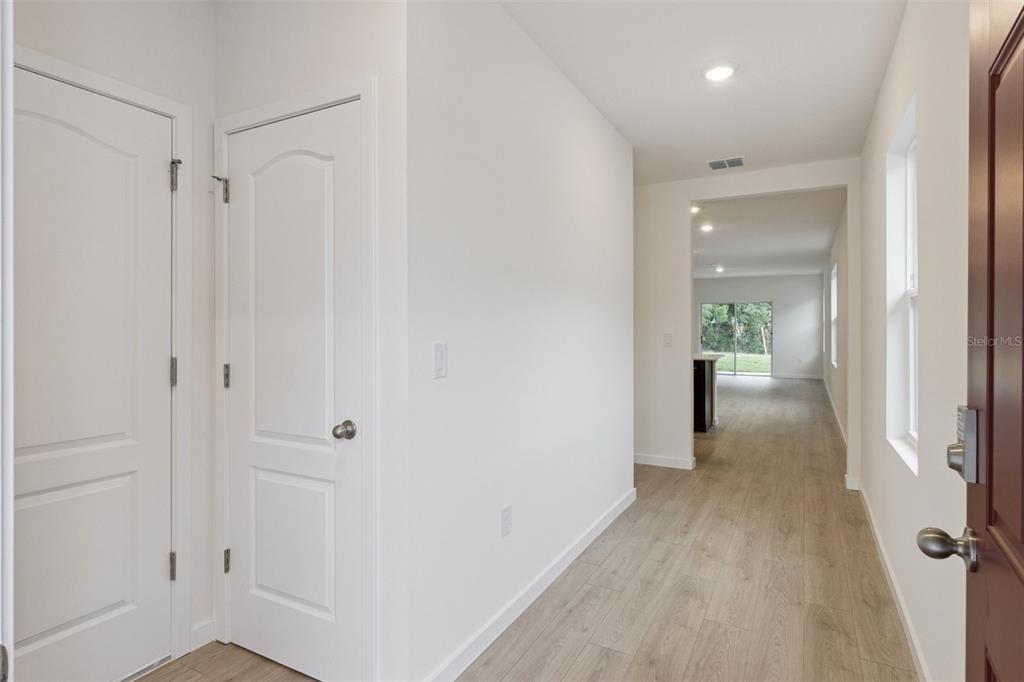 A bright entryway with light wood-look flooring leads into an open-concept living area — 1912 HOWARD MESA DRIVE, KISSIMMEE, FL