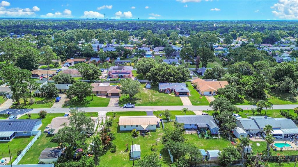 An aerial view shows a suburban neighborhood with single-family homes, green lawns, and mature trees — 2820 SABAL PALM DRIVE, EDGEWATER, FL