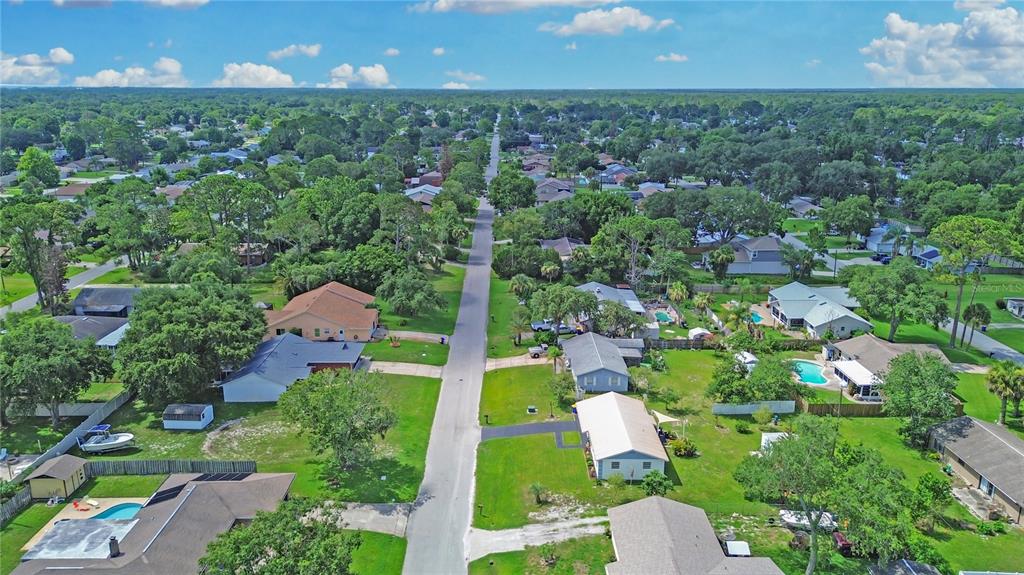 An aerial view shows a residential street lined with houses, green lawns, and mature trees — 2820 SABAL PALM DRIVE, EDGEWATER, FL