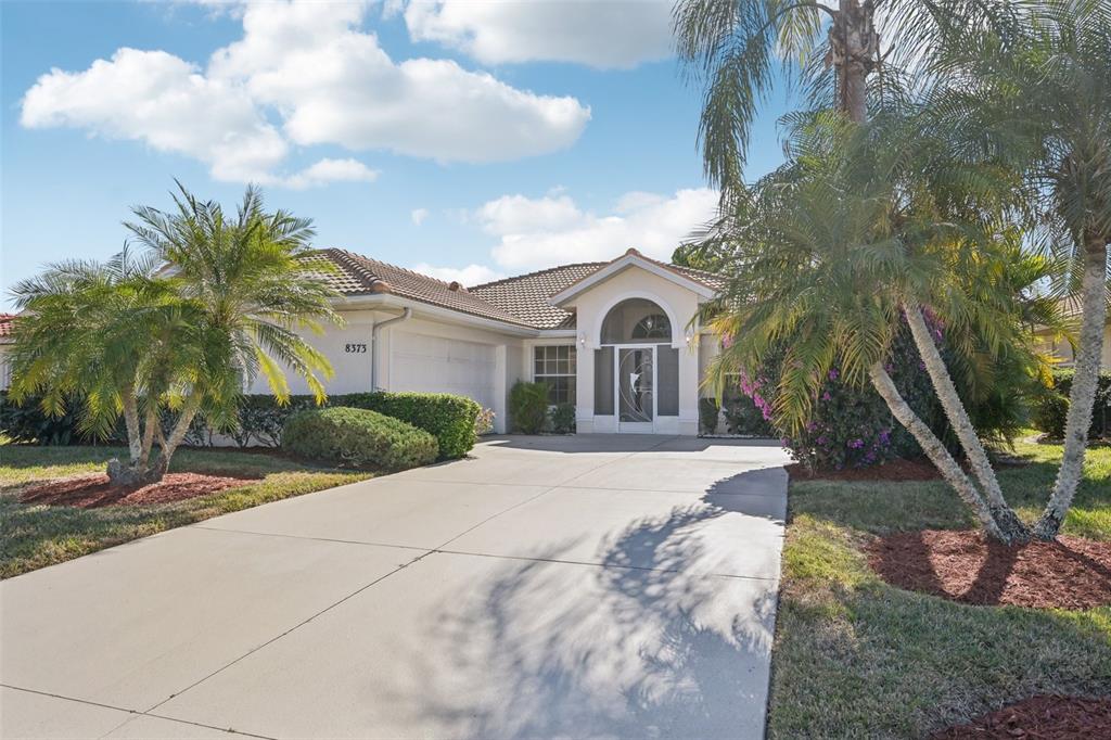 A single-story house with a tile roof, a concrete driveway, and palm trees in front — 8373 PONDVIEW LANE, ENGLEWOOD, FL