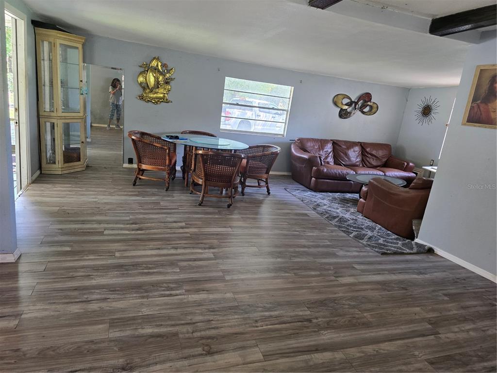 A kitchen with white cabinets, marble-look tile backsplash, a glass dining table, and wood-look flooring — 5302 SWAYING PALM DRIVE, PUNTA GORDA, FL