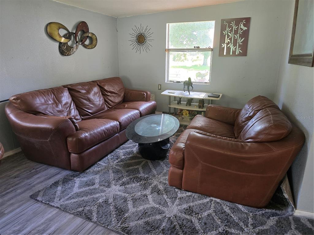 A living and dining area features wood-look flooring, a leather sofa, and a glass table — 5302 SWAYING PALM DRIVE, PUNTA GORDA, FL