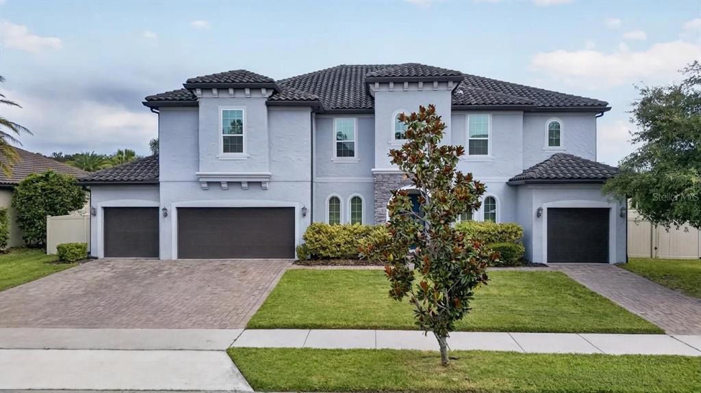 A two-story house with a light blue exterior, a tile roof, and a three-car garage — 659 RED HAVEN LANE, OVIEDO, FL