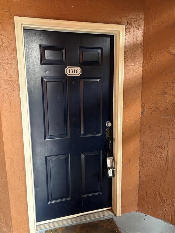 A dark blue front door with a lockbox is set into a textured orange wall — 5152 CONROY ROAD UNIT 1316, ORLANDO, FL