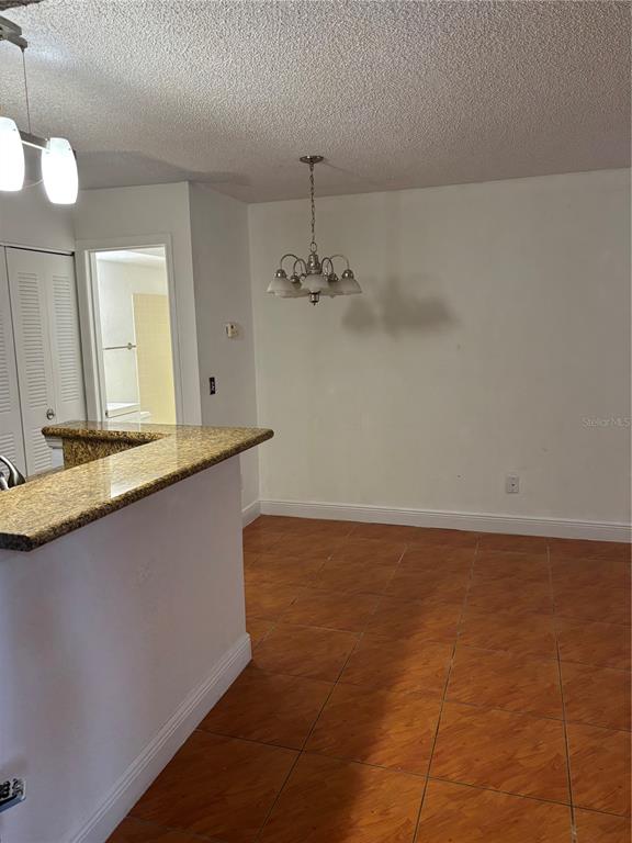 A dining area features orange tile flooring, a chandelier, and a granite-topped breakfast bar — 5152 CONROY ROAD UNIT 1316, ORLANDO, FL