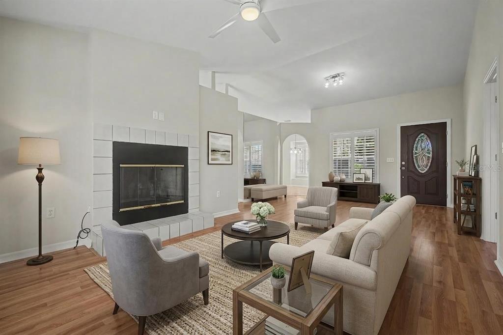 A living room features a fireplace, hardwood floors, a ceiling fan, and neutral furniture — 6208 HUNTINGTON DRIVE, ZEPHYRHILLS, FL