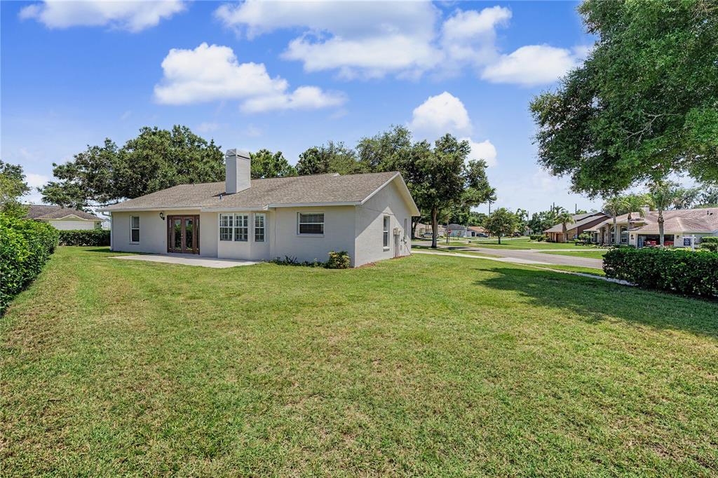 The exterior of a single-story house features a light-colored facade, a chimney, and a lawn — 6208 HUNTINGTON DRIVE, ZEPHYRHILLS, FL