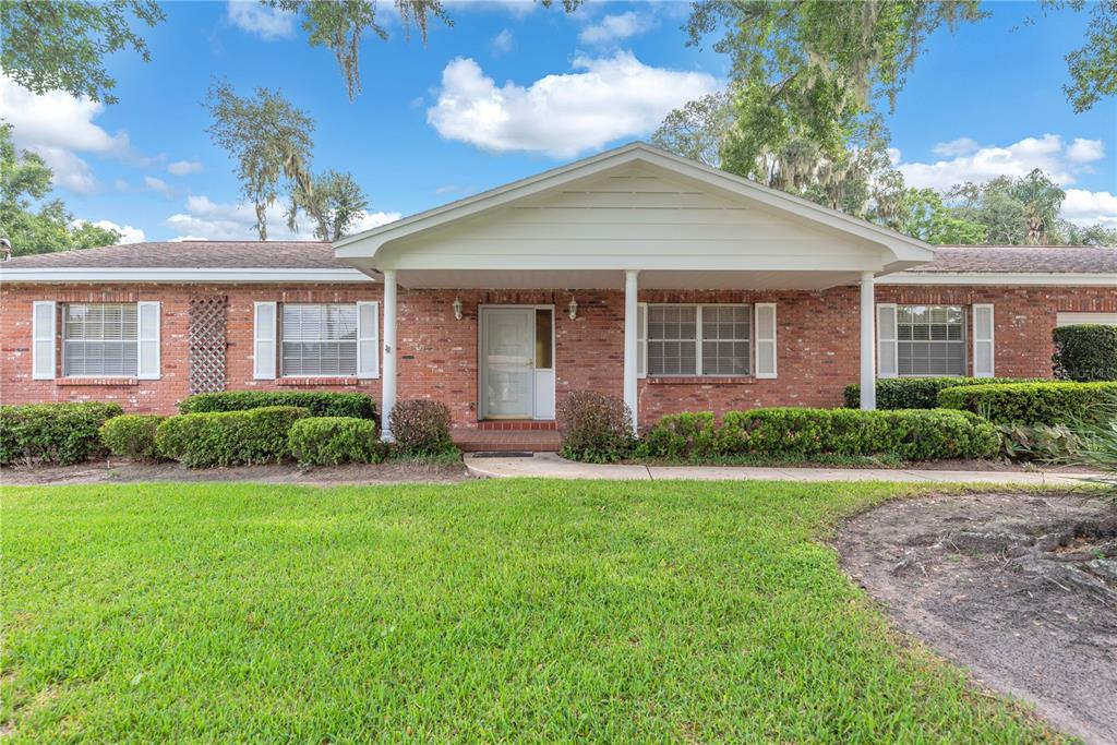 A single-story brick house with a covered front porch and a green lawn — 110 ASHBROOK DRIVE, BRANDON, FL