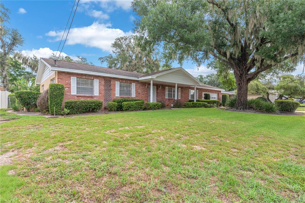 A single-story brick house with a covered front porch and a large tree in front — 110 ASHBROOK DRIVE, BRANDON, FL
