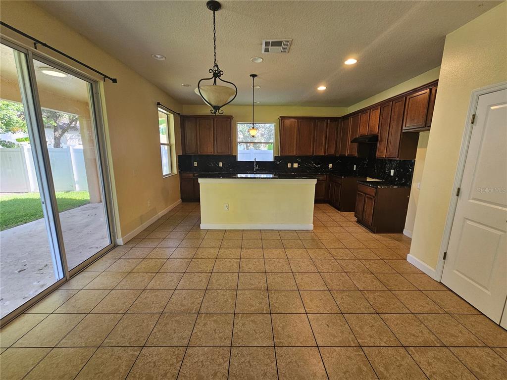 A kitchen with dark wood cabinets, black countertops, a central island, and tile flooring — 5013 BALLARK STREET, MOUNT DORA, FL
