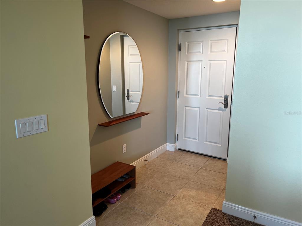 An entryway features a tiled floor, a wall-mounted mirror with a shelf, and a shoe rack — 800 N TAMIAMI TRAIL UNIT 905, SARASOTA, FL