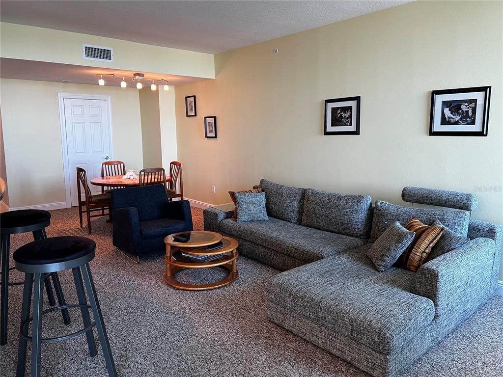 A living room with a gray sectional sofa, a round coffee table, and a dining area — 800 N TAMIAMI TRAIL UNIT 905, SARASOTA, FL