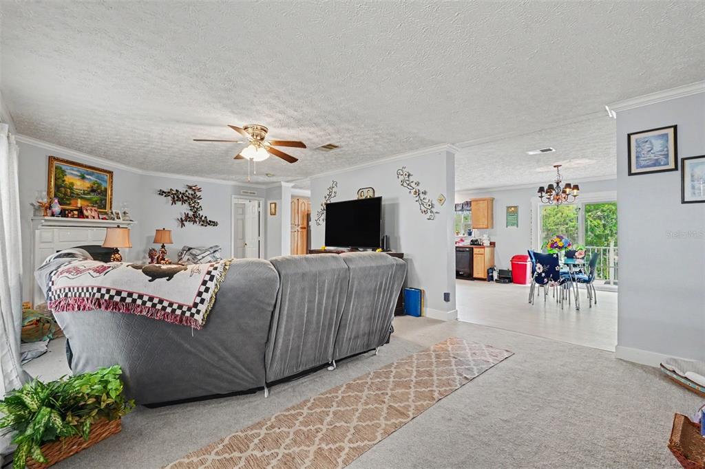 A living room with gray carpet and a sectional sofa opens into a dining area — 8043 TOWER STREET, BROOKSVILLE, FL