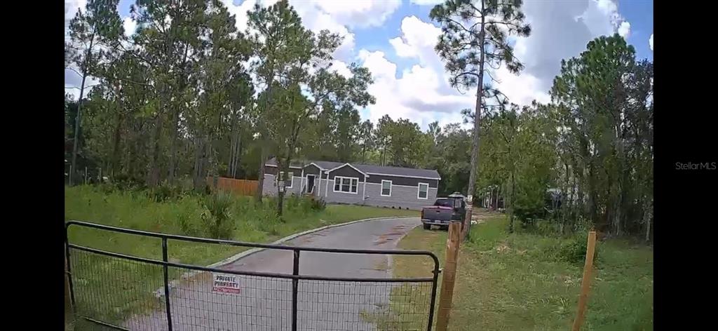 A single-story house sits at the end of a paved driveway behind a metal gate — 5590 W X ANNE LANE, DUNNELLON, FL