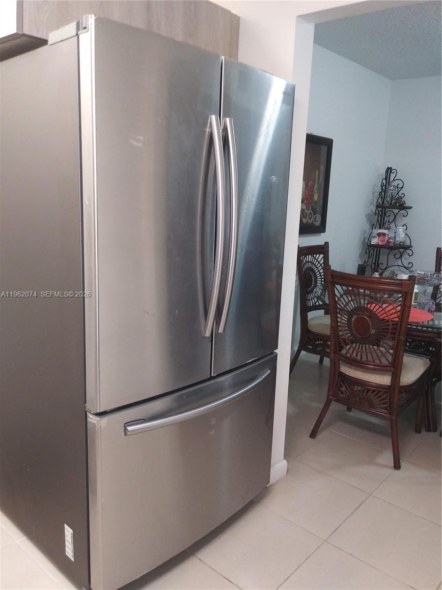 A stainless steel French door refrigerator stands in a kitchen next to a dining area — 4172 Inverrary Dr # 310, Lauderhill FL 33319, LAUDERHILL, FL
