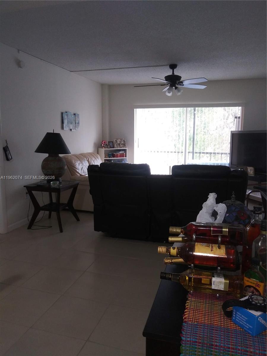 A living room features a dark ceiling fan, tiled floors, and a sliding glass door — 4172 Inverrary Dr # 310, Lauderhill FL 33319, LAUDERHILL, FL