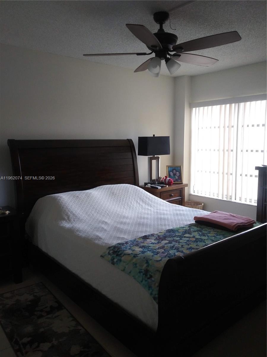 A bedroom features a dark wood sleigh bed, a ceiling fan, and vertical window blinds — 4172 Inverrary Dr # 310, Lauderhill FL 33319, LAUDERHILL, FL