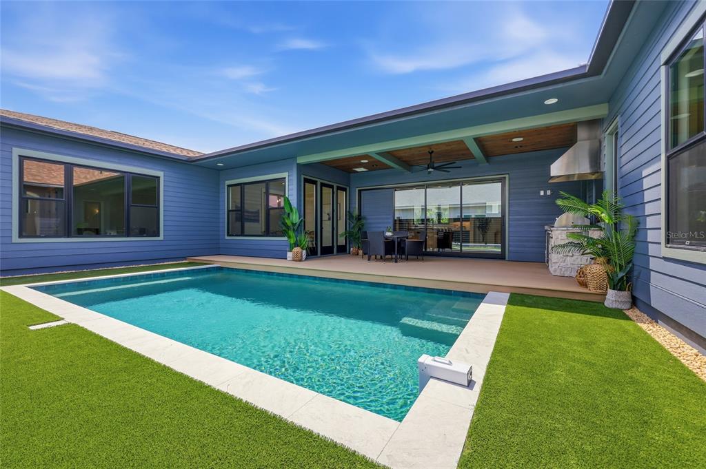 A backyard features a swimming pool, a covered patio with an outdoor kitchen, and blue siding — 13233 SW 11 ROAD, NEWBERRY, FL