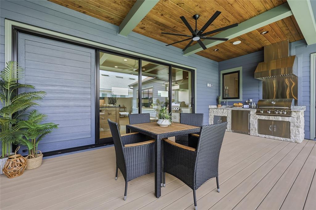 A covered outdoor patio features a dining set, a built-in grill, and wood-paneled ceilings — 13233 SW 11 ROAD, NEWBERRY, FL