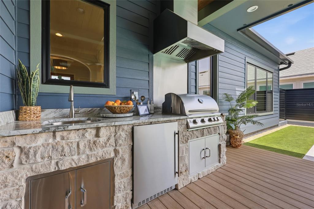 An outdoor kitchen features a stone base, stainless steel appliances, and a sink on a deck — 13233 SW 11 ROAD, NEWBERRY, FL