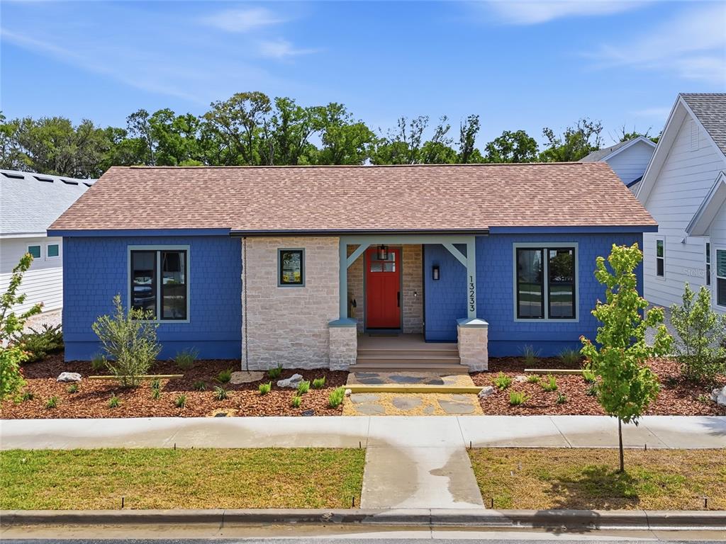 A blue house with a stone facade, red front door, and brown shingled roof — 13233 SW 11 ROAD, NEWBERRY, FL