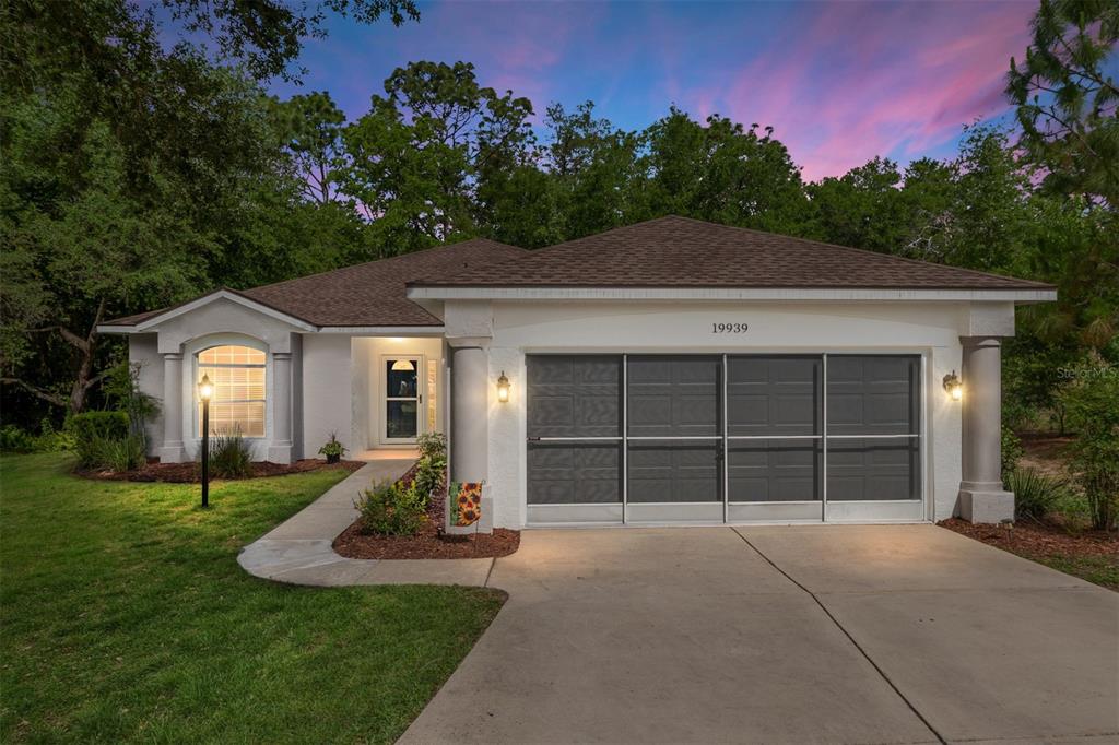 A single-story house with a brown roof, white stucco exterior, and a two-car garage — 19939 SW 93RD LANE, DUNNELLON, FL
