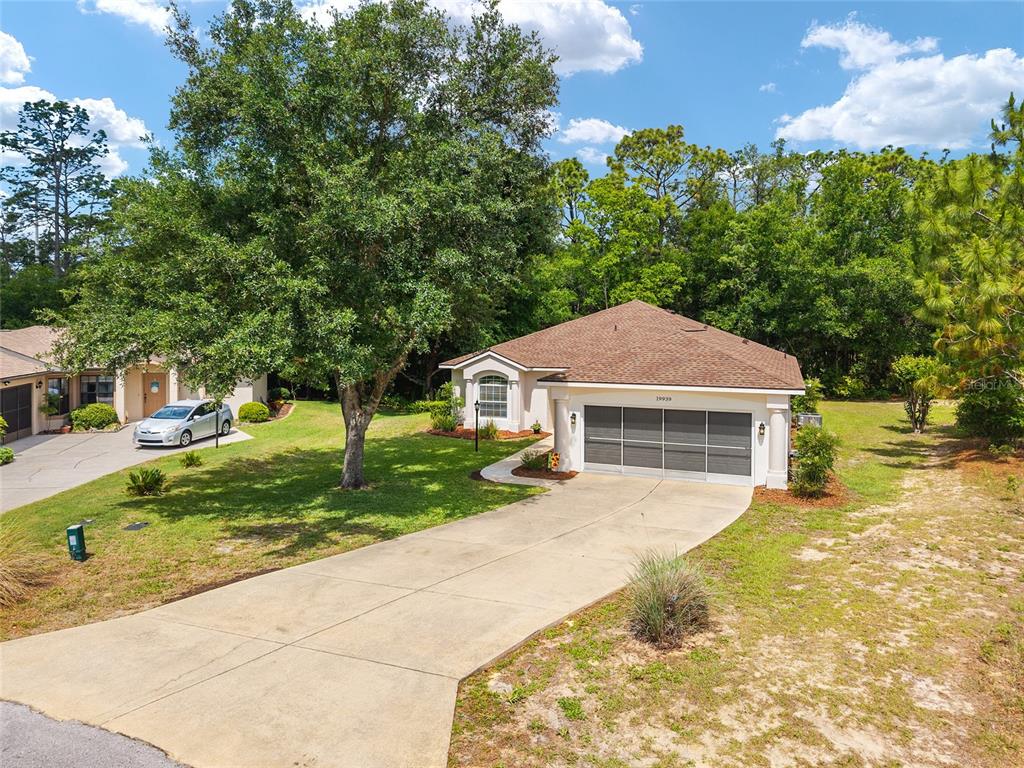 A single-story house with a two-car garage and a concrete driveway sits on a lot — 19939 SW 93RD LANE, DUNNELLON, FL