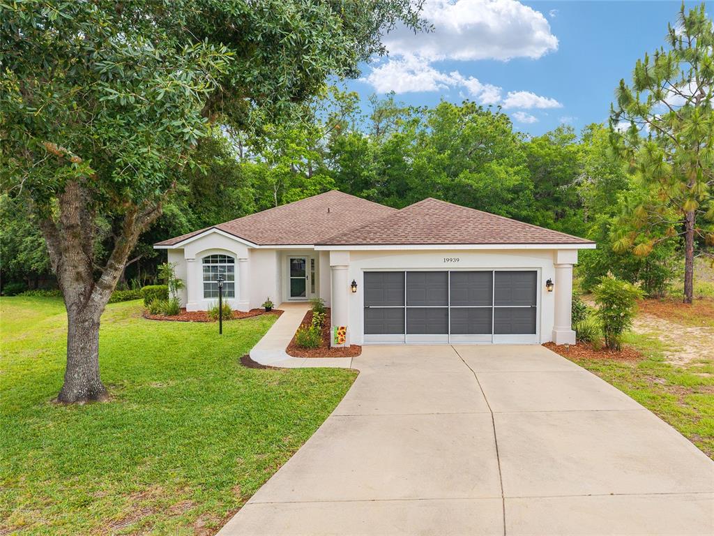 A single-story house with a brown shingled roof, a two-car garage, and a concrete driveway — 19939 SW 93RD LANE, DUNNELLON, FL