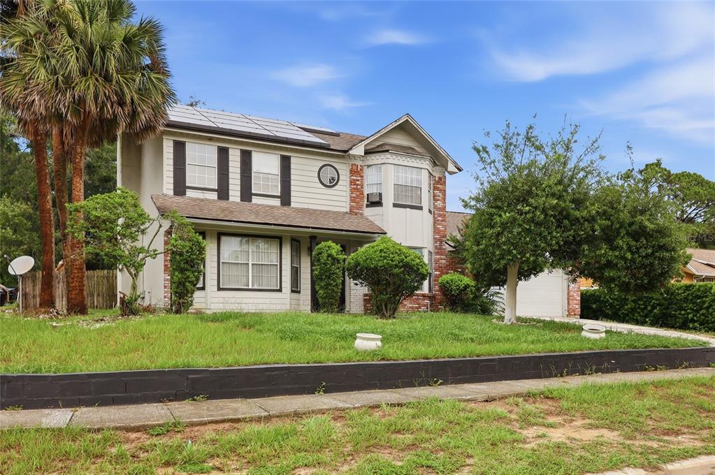 A two-story house with light siding, a brick accent wall, and solar panels on the roof — 6923 COLONY OAKS LANE, ORLANDO, FL