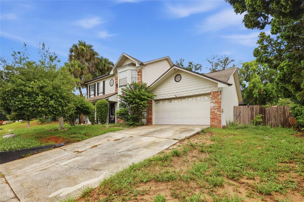 A two-story house with a white garage, brick accents, and a concrete driveway — 6923 COLONY OAKS LANE, ORLANDO, FL