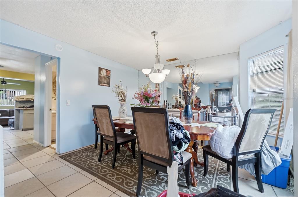 A dining room features a wooden table, upholstered chairs, a patterned rug, and mirrored walls — 6923 COLONY OAKS LANE, ORLANDO, FL