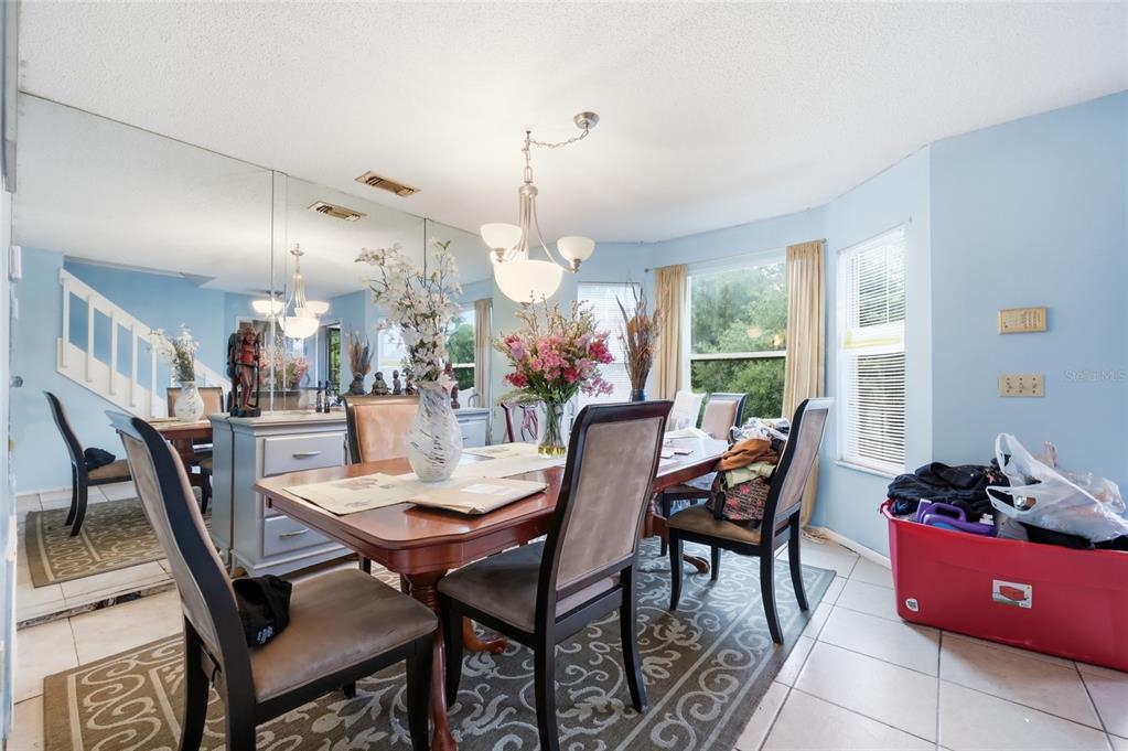 A dining room with a wooden table, chairs, a mirrored wall, and light blue walls — 6923 COLONY OAKS LANE, ORLANDO, FL
