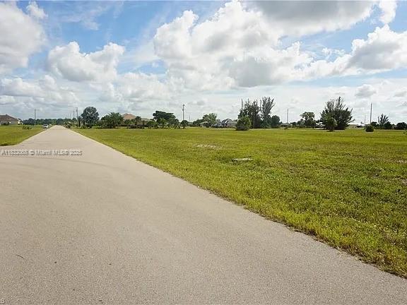 A paved road runs alongside a large, flat, grassy vacant lot under a cloudy sky — 4500 NW 34th Ter, Cape Coral FL 33993, CAPE CORAL, FL