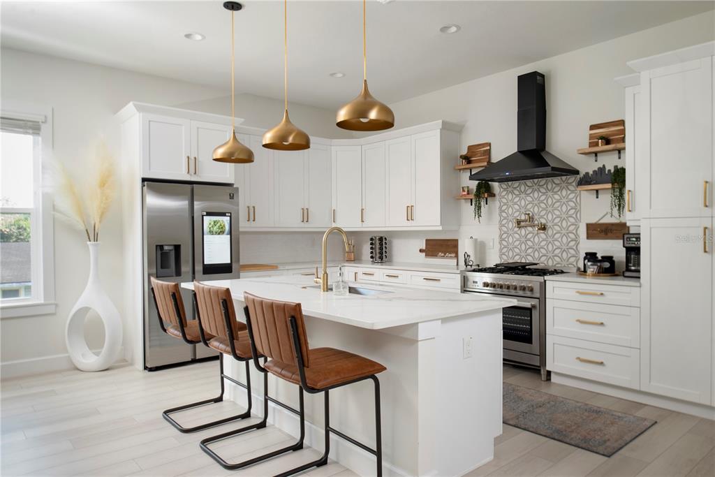 A modern kitchen features white cabinetry, a central island with bar stools, and gold pendant lights — 4919 N NEBRASKA AVENUE, TAMPA, FL