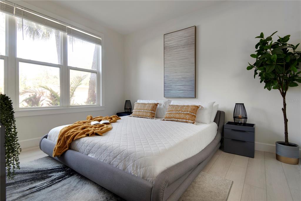 A bedroom features a gray upholstered bed, a tall abstract painting, and a potted plant — 4919 N NEBRASKA AVENUE, TAMPA, FL