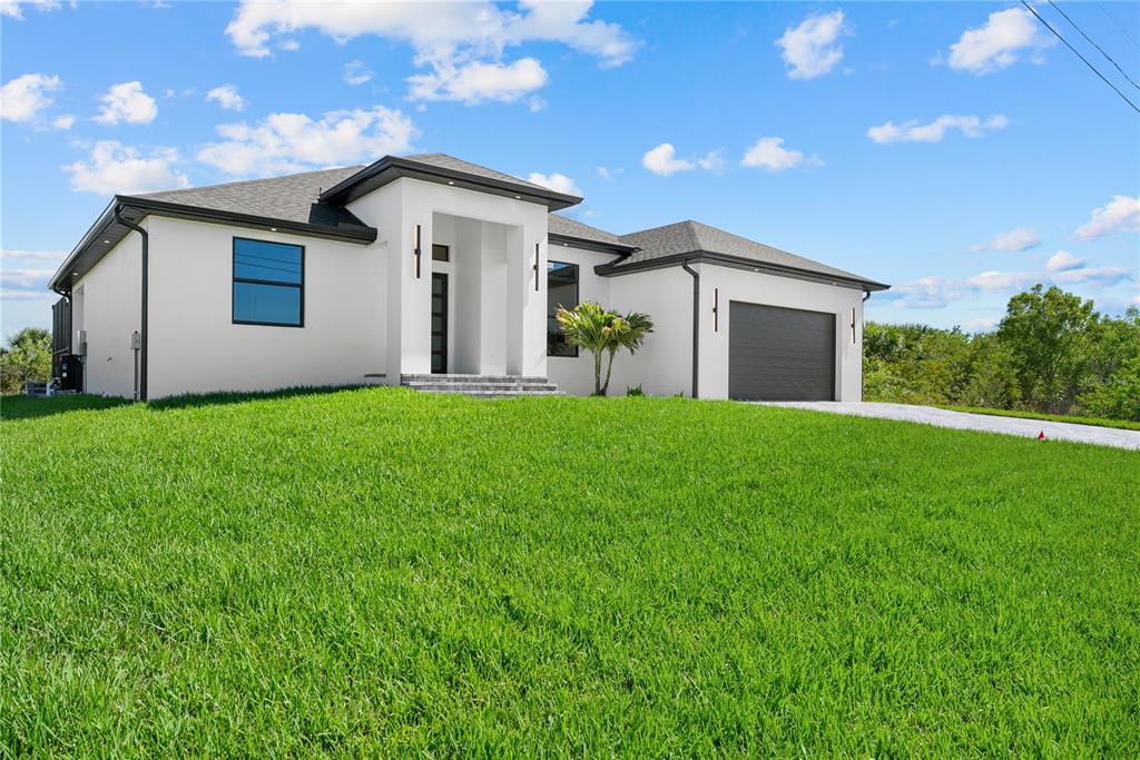 A modern, white single-story house with a dark roof and garage sits on a lawn — 15101 LEIPZIG CIRCLE, PORT CHARLOTTE, FL