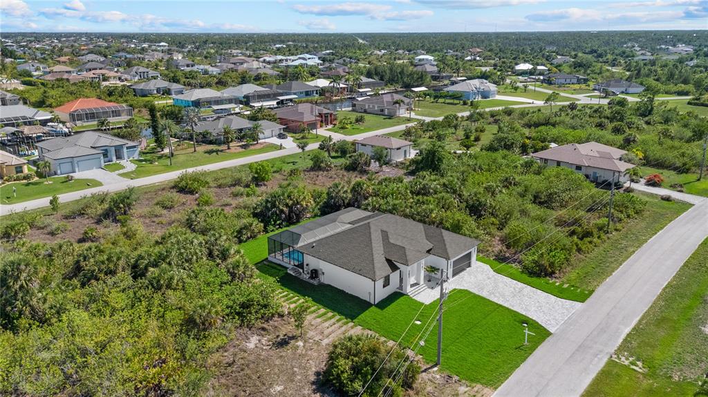 An aerial view shows a modern single-story house with a pool cage and paved driveway — 15101 LEIPZIG CIRCLE, PORT CHARLOTTE, FL