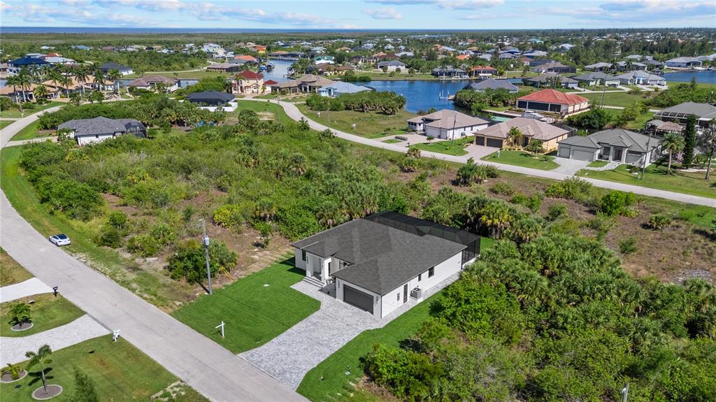 An aerial view shows a modern single-story house with a gray roof and paved driveway — 15101 LEIPZIG CIRCLE, PORT CHARLOTTE, FL
