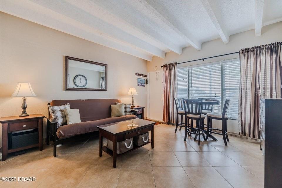 A living and dining area features tile floors, a brown futon, and a dining set — 935 S ATLANTIC AVENUE UNIT 128, DAYTONA BEACH, FL