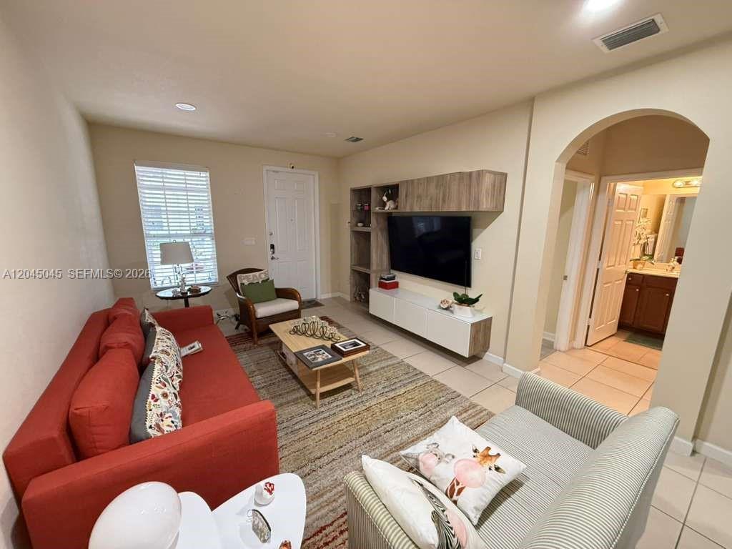 A living room features a red sofa, a striped armchair, a television, and tile flooring — 9572 SW 169th Pl, Miami FL 33196, MIAMI, FL