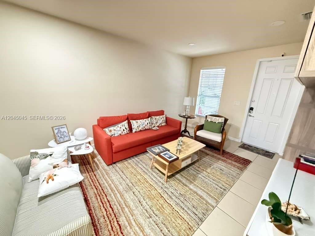 A living room features a red sofa, a patterned area rug, and a white door — 9572 SW 169th Pl, Miami FL 33196, MIAMI, FL