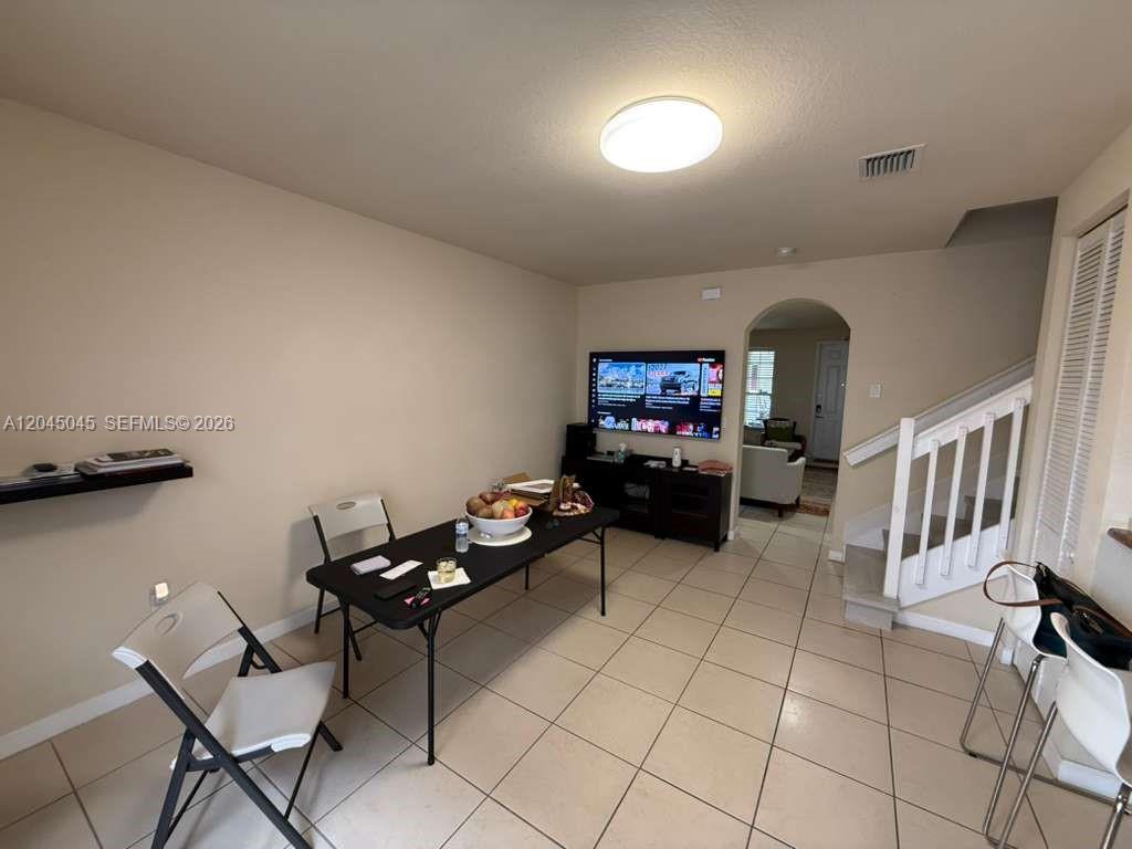 A dining area features a folding table, white chairs, tile flooring, and a wall-mounted television — 9572 SW 169th Pl, Miami FL 33196, MIAMI, FL