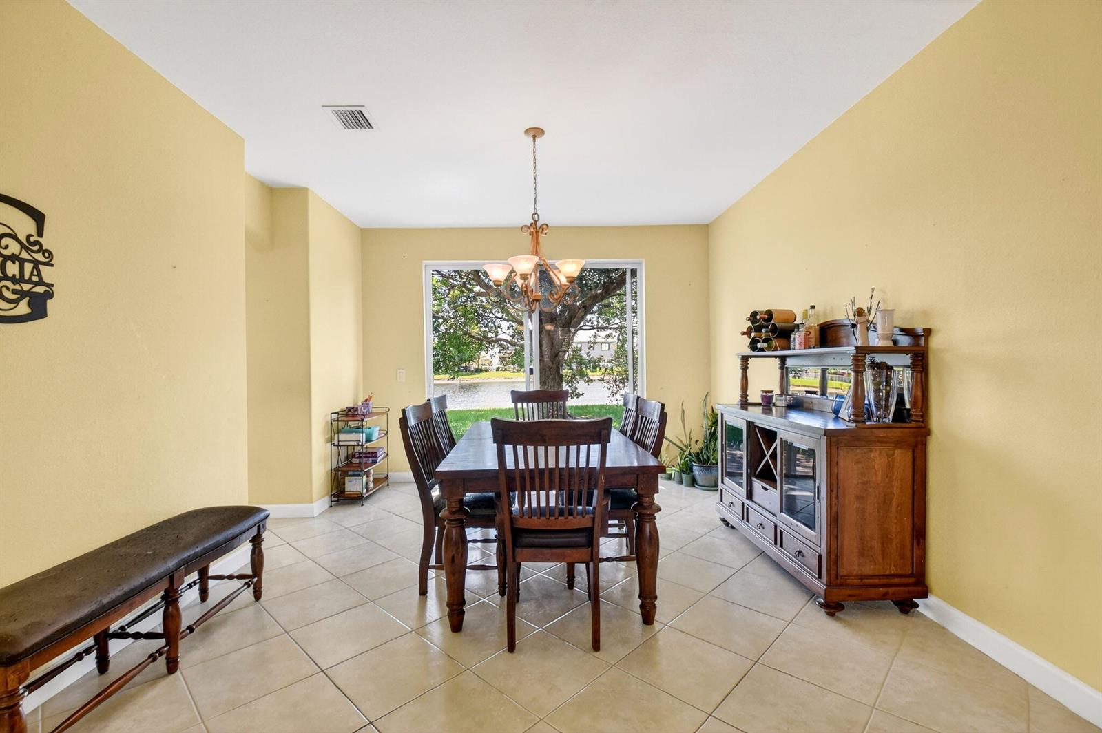 A dining room features a wooden table, chairs, a hutch, and a large window view — 10624 Old Hammock Way, Wellington FL 33414, WELLINGTON, FL