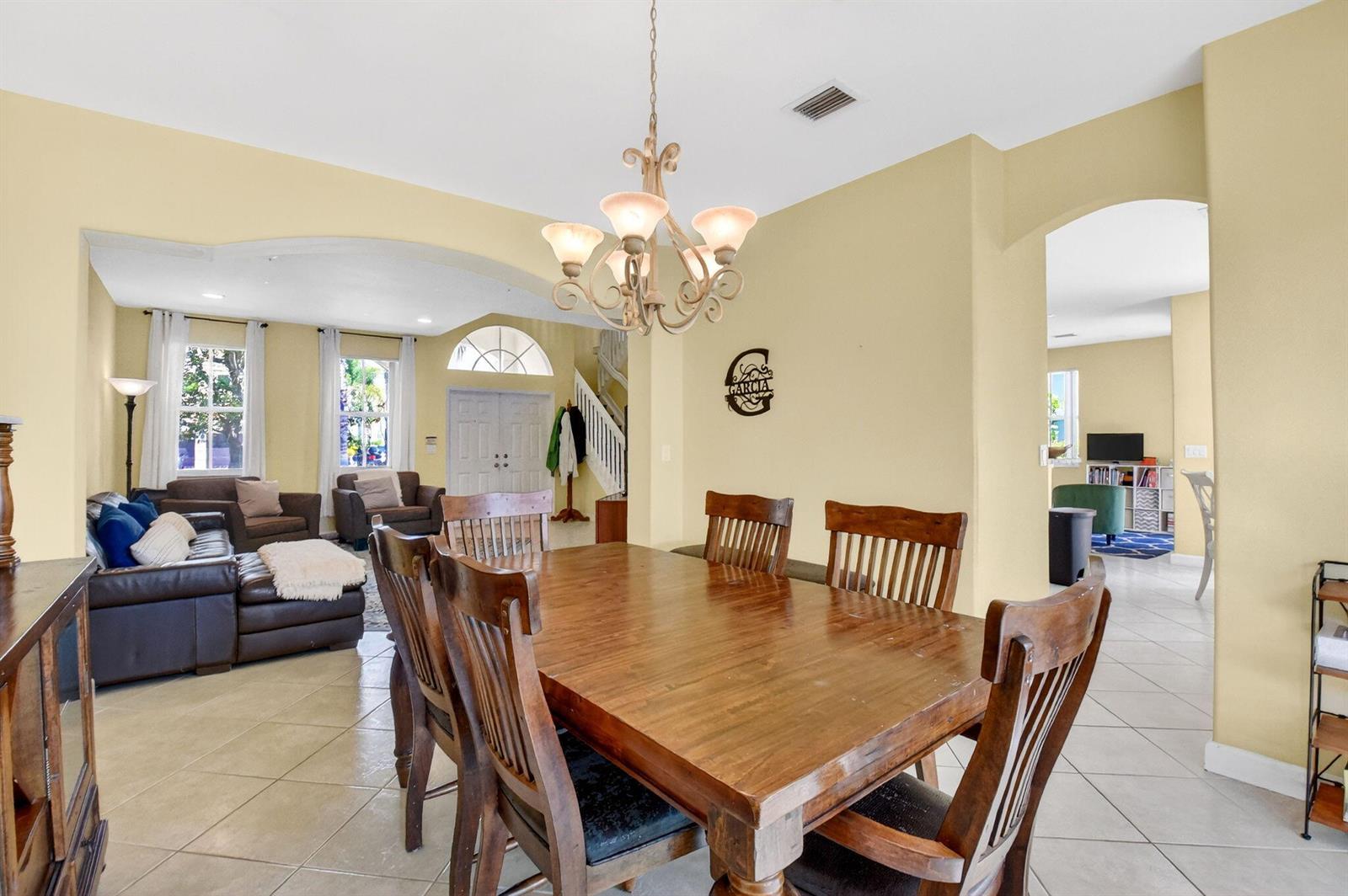 A dining room with a wooden table and chairs sits adjacent to a living area — 10624 Old Hammock Way, Wellington FL 33414, WELLINGTON, FL