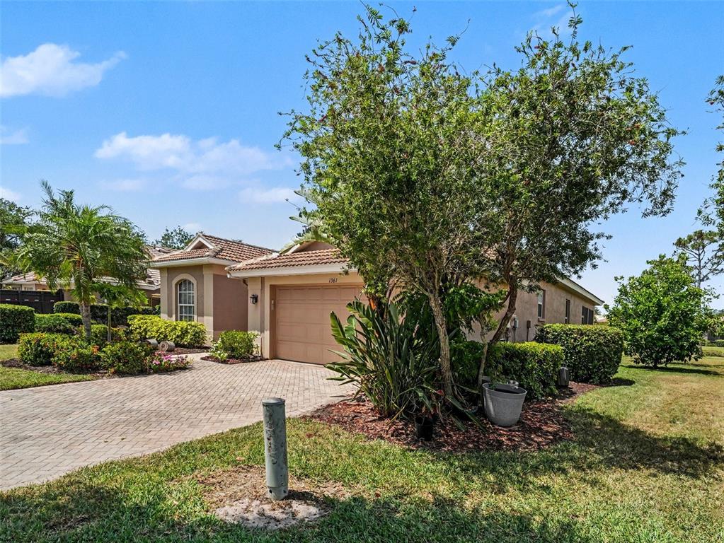 A single-story house with a paved driveway, a two-car garage, and mature landscaping — 1361 NEW FOREST LANE, OSPREY, FL