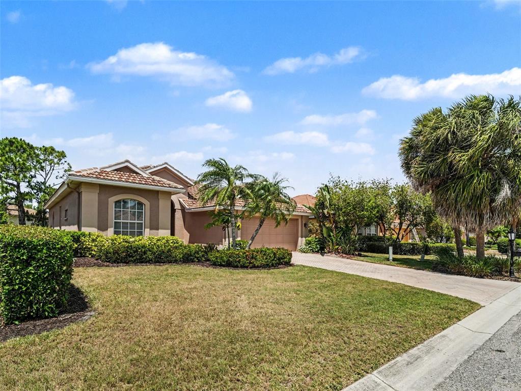 A single-story house with a tan exterior, a tiled roof, and a paved driveway — 1361 NEW FOREST LANE, OSPREY, FL