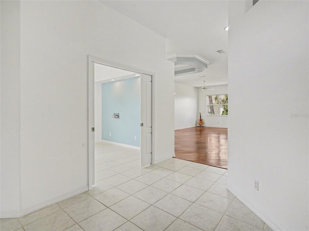 A tiled entryway leads to a light blue room and a living area with wood floors — 1361 NEW FOREST LANE, OSPREY, FL